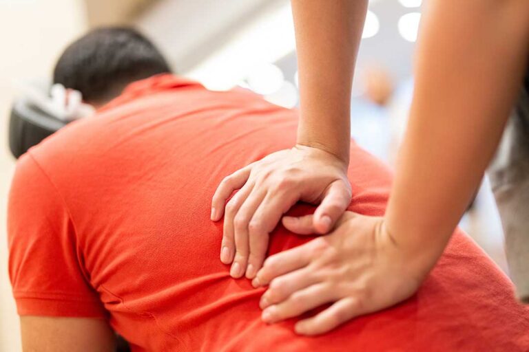 A person gently stretching their neck while sitting in a bright, comfortable living room.