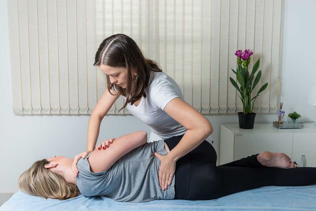 Person gently stretching their lower back beside a window after light household activity.